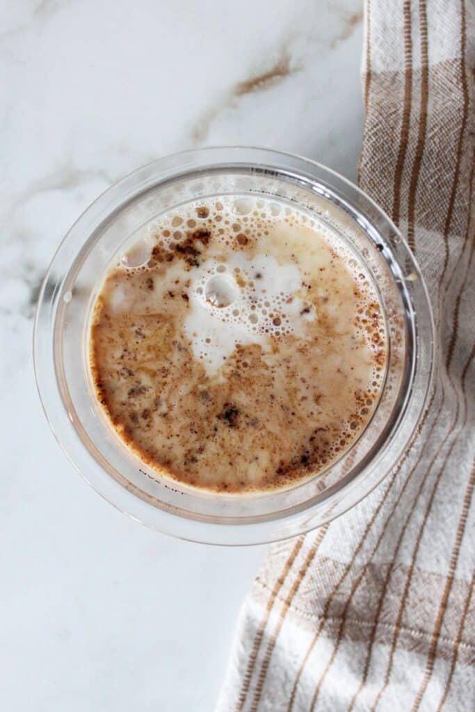 An overhead shot of milk, instant coffee, maple syrup and vanilla extract in a ninja creami container.