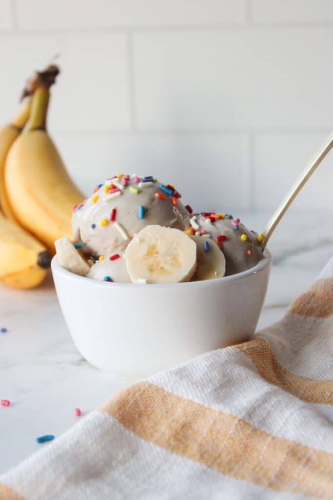 A small white bowl of Ninja creami banana ice cream with colorful sprinkles.