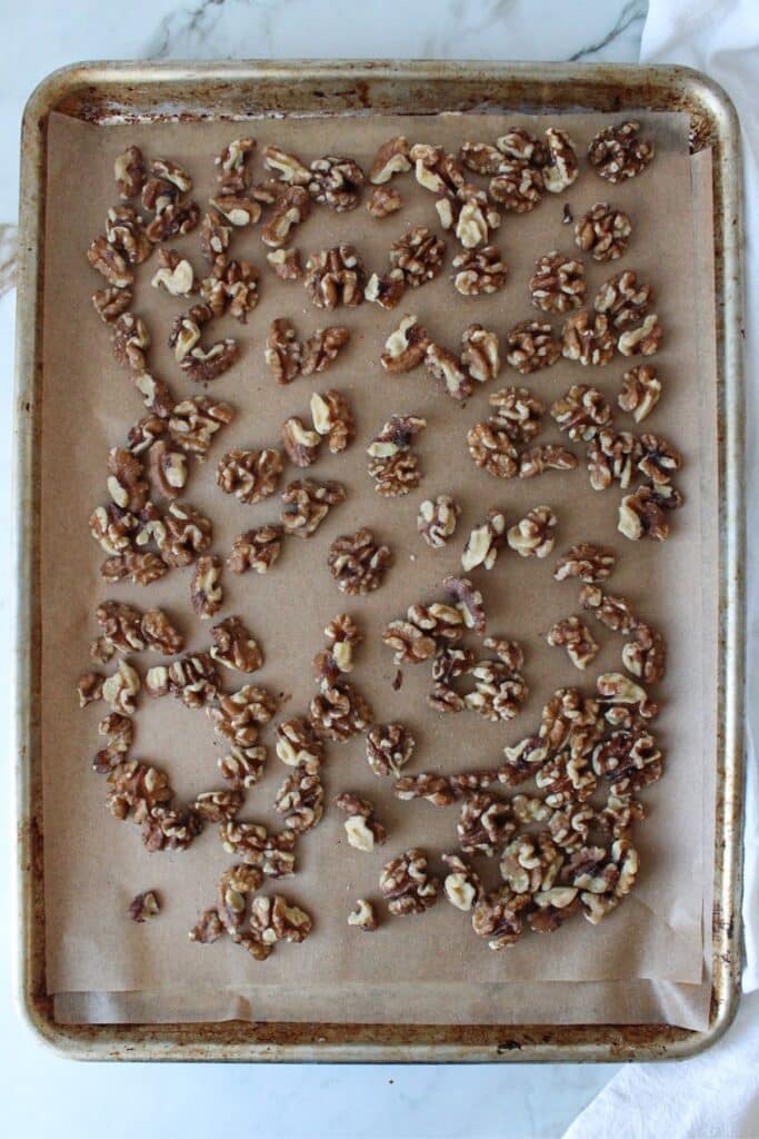 Roasted walnuts on a sheet pan lined with parchment paper.