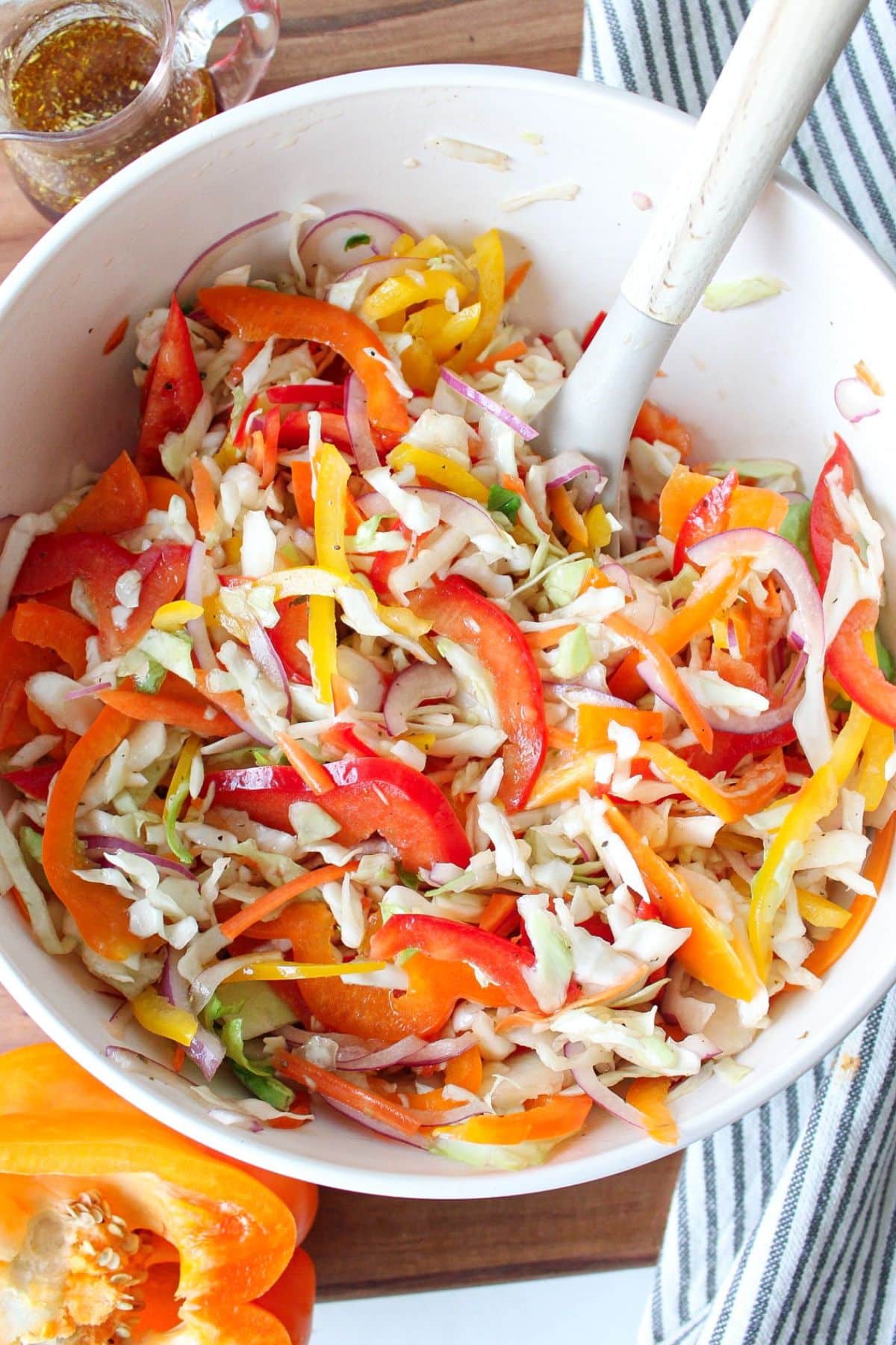 Bell pepper slaw in a white bowl with a serving spoon.