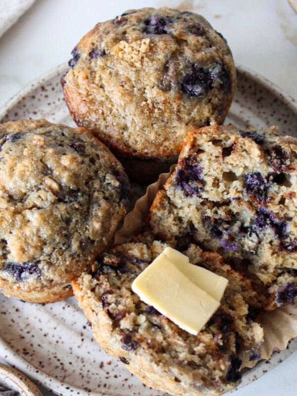 Blueberry chocolate chip muffins on a plate with butter.