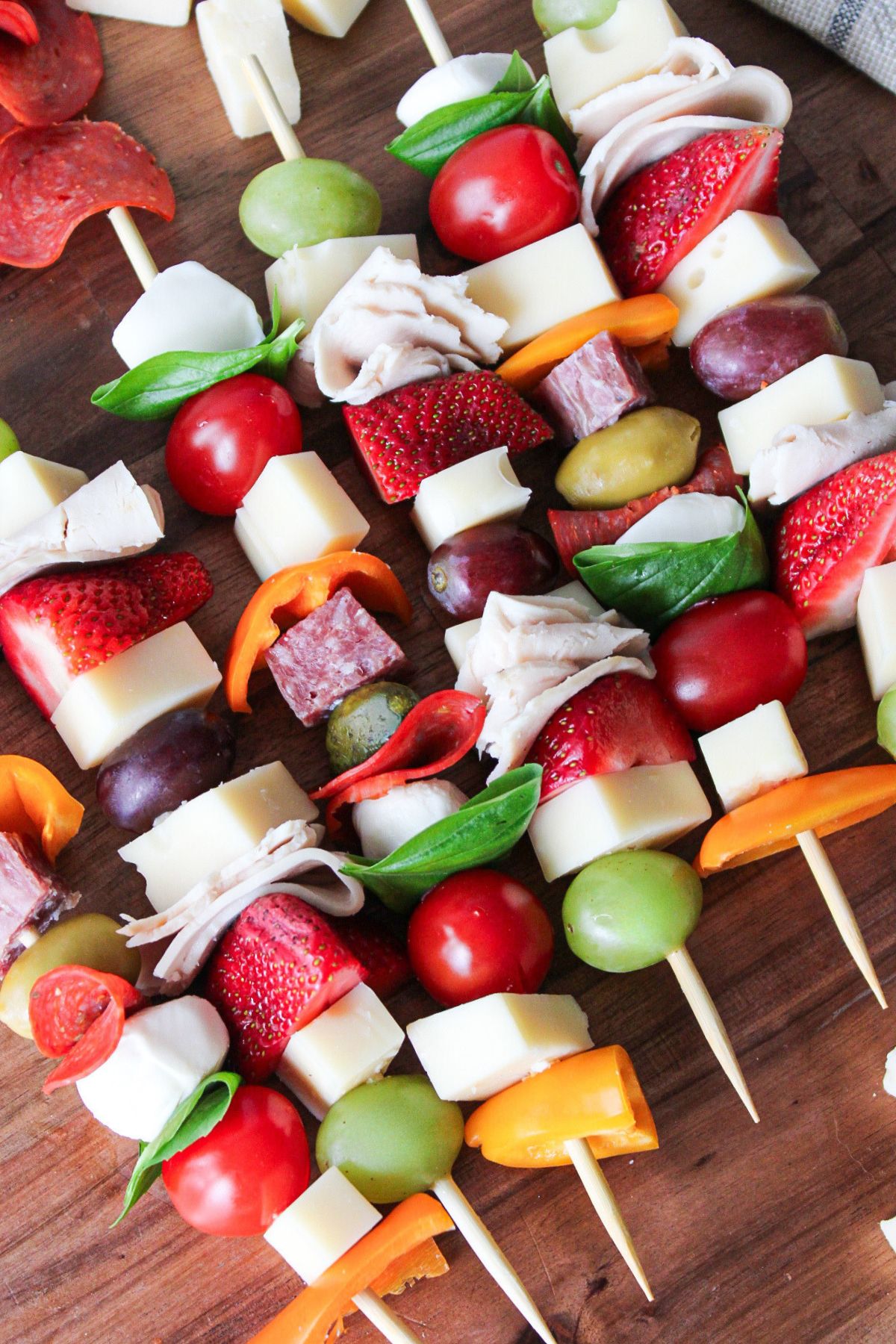 Charcuterie skewers arranged on a wooden board.