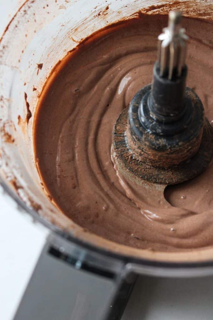 A close up shot of blended cottage cheese chocolate mousse in a food processor.