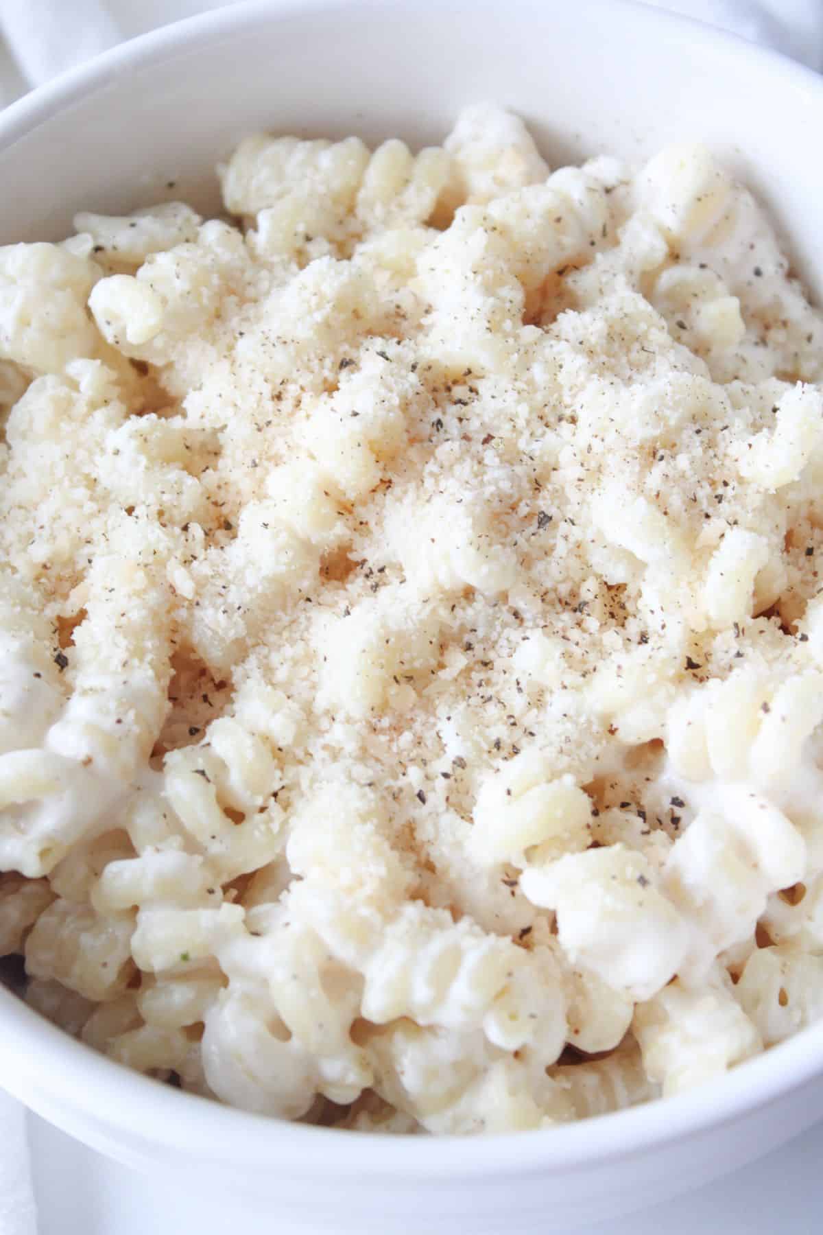 A bowl full of cottage cheese pasta sauce on chickpea pasta and topped with parmesan cheese and black pepper.