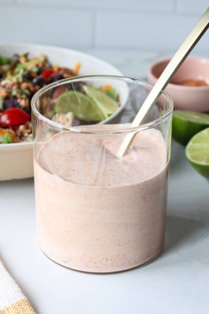 Greek yogurt taco sauce in a glass container with a gold spoon.