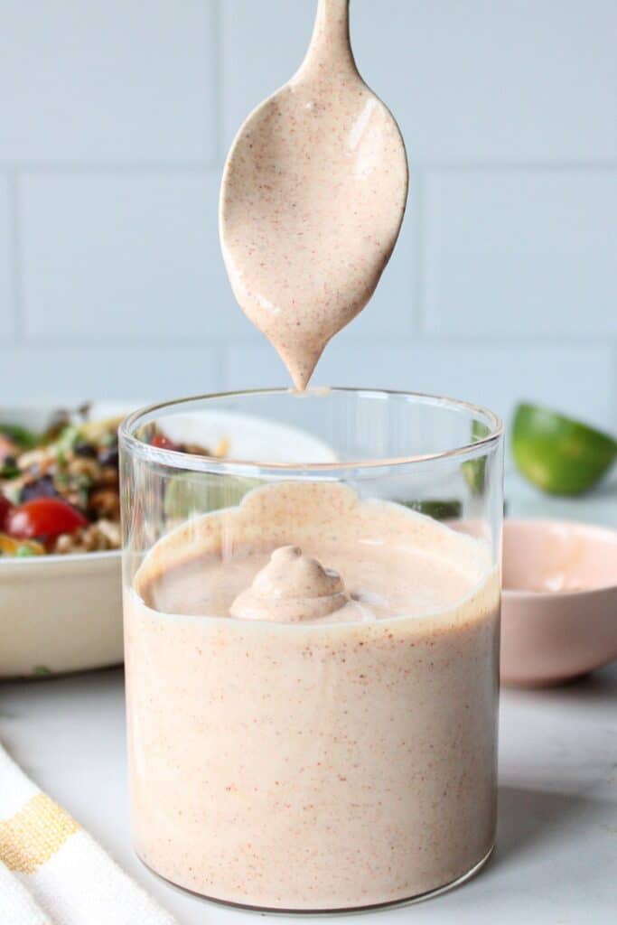 A spoonful of Greek yogurt taco sauce above a full container.