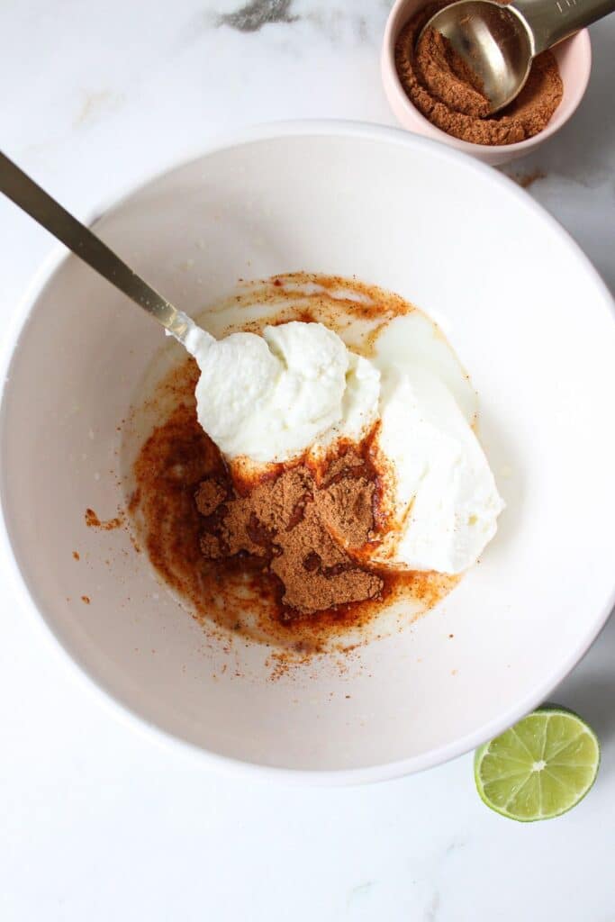 Greek yogurt, taco seasoning, milk and lime juice in a bowl, not yet mixed.