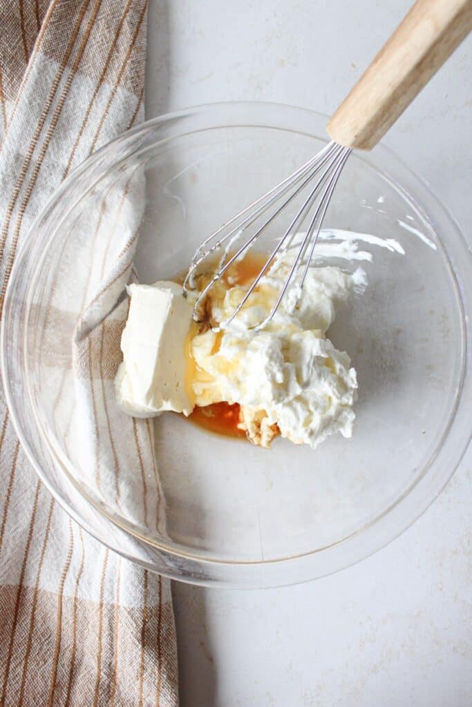 Greek yogurt, cream cheese, honey, vanilla extract, lemon juice and graham crackers in a bowl.