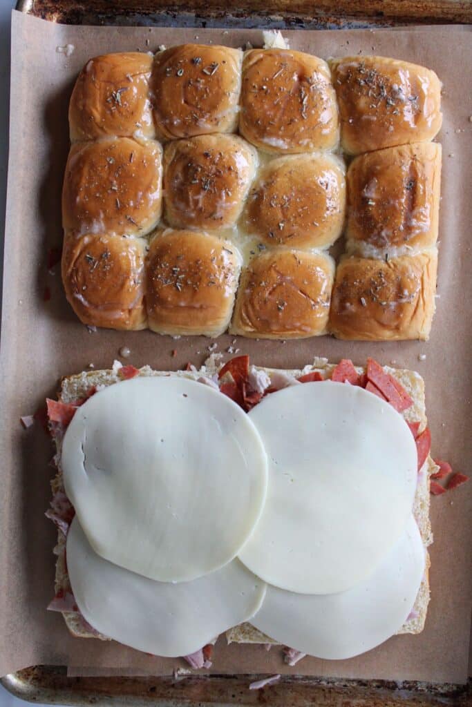 Slider buns topped with chopped meats and provolone cheese.