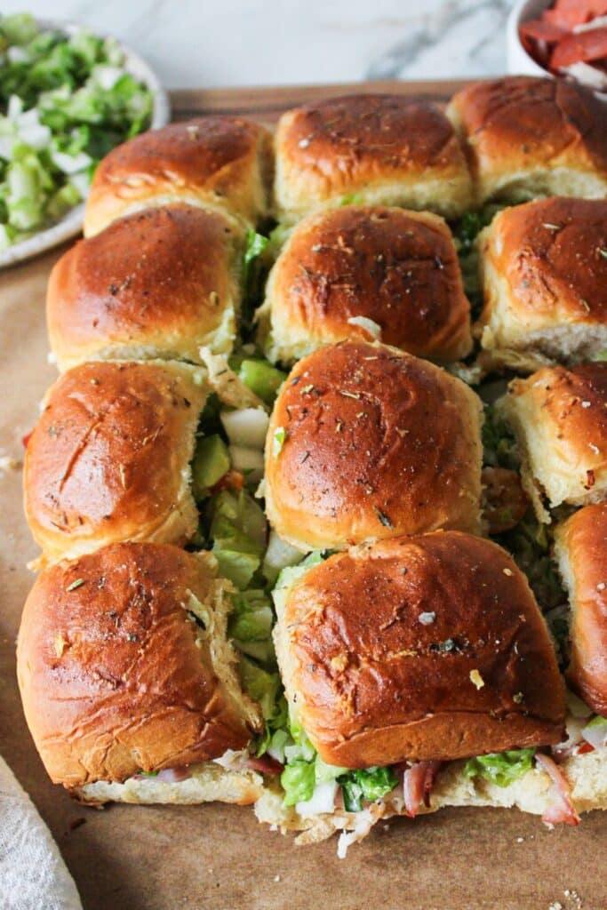 A close up shot of chopped italian sliders on parchment paper.