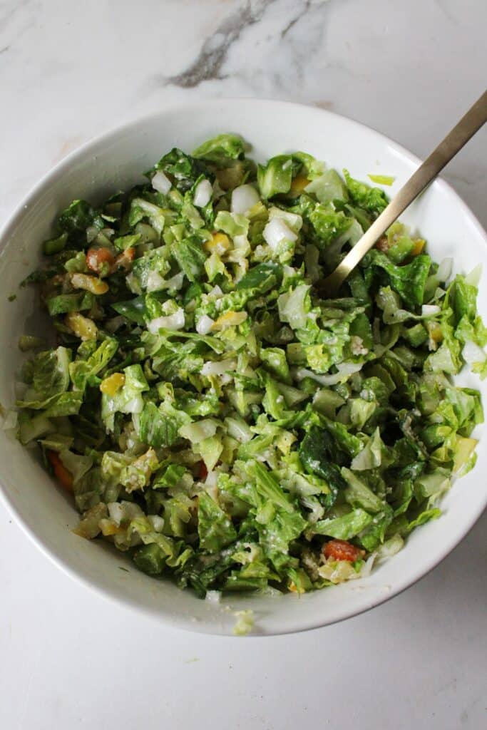 Chopped salad mixed with dressing in a bowl.
