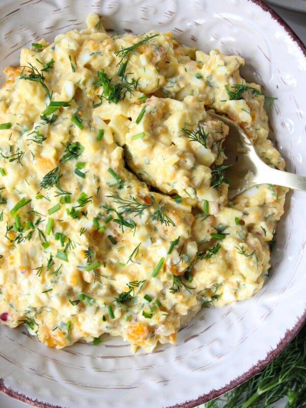 Cottage cheese egg salad in a bowl garnished with chives served with a spoon.