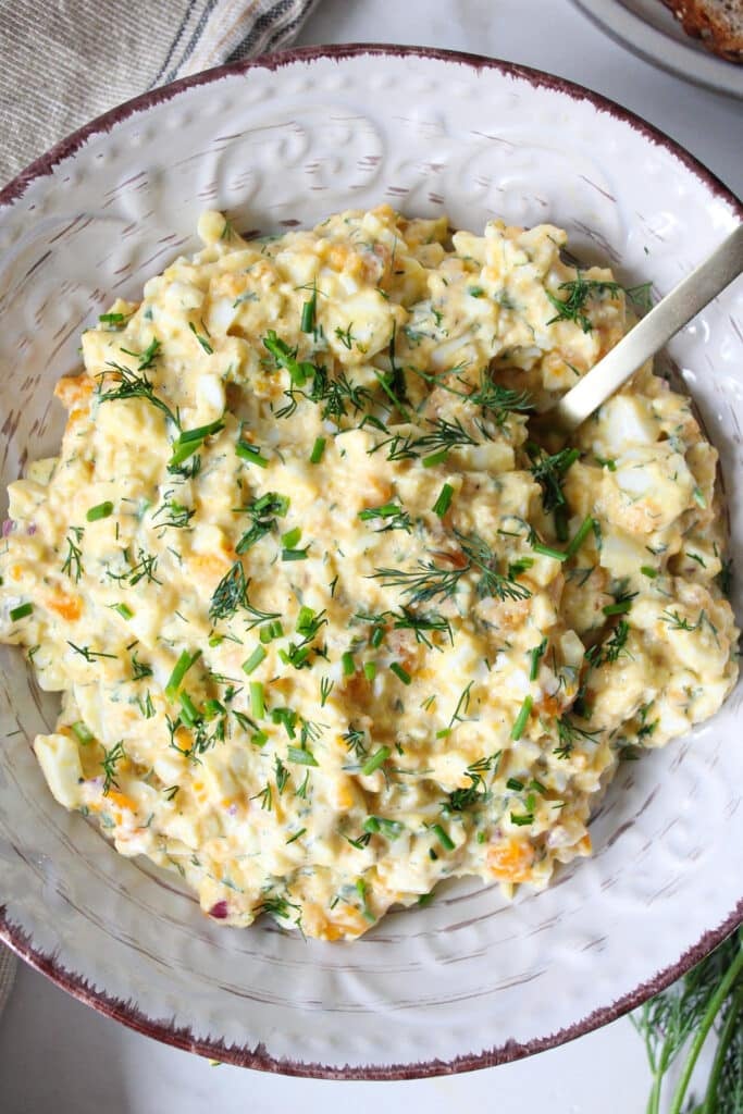 A close up shot of cottage cheese egg salad garnished with chives and dill.