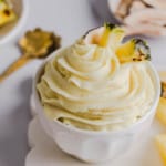 The dole whip in a white bowl garnished with pineapple on a white countertop.