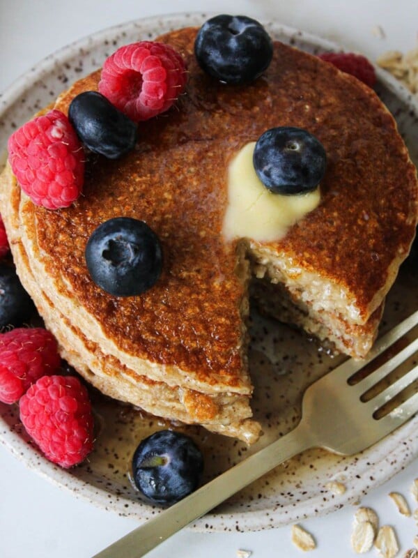 A stack of oatmeal cottage cheese pancakes with a bite carved out and a fork.
