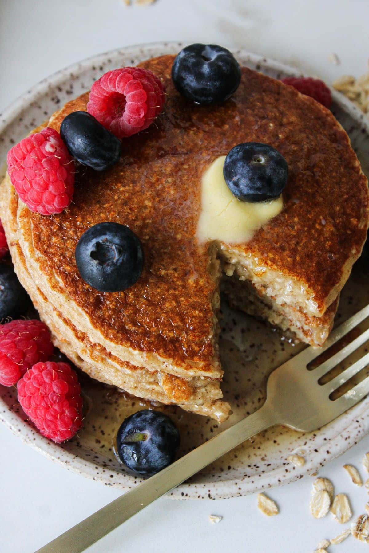 A stack of oatmeal cottage cheese pancakes with a bite carved out and a fork.