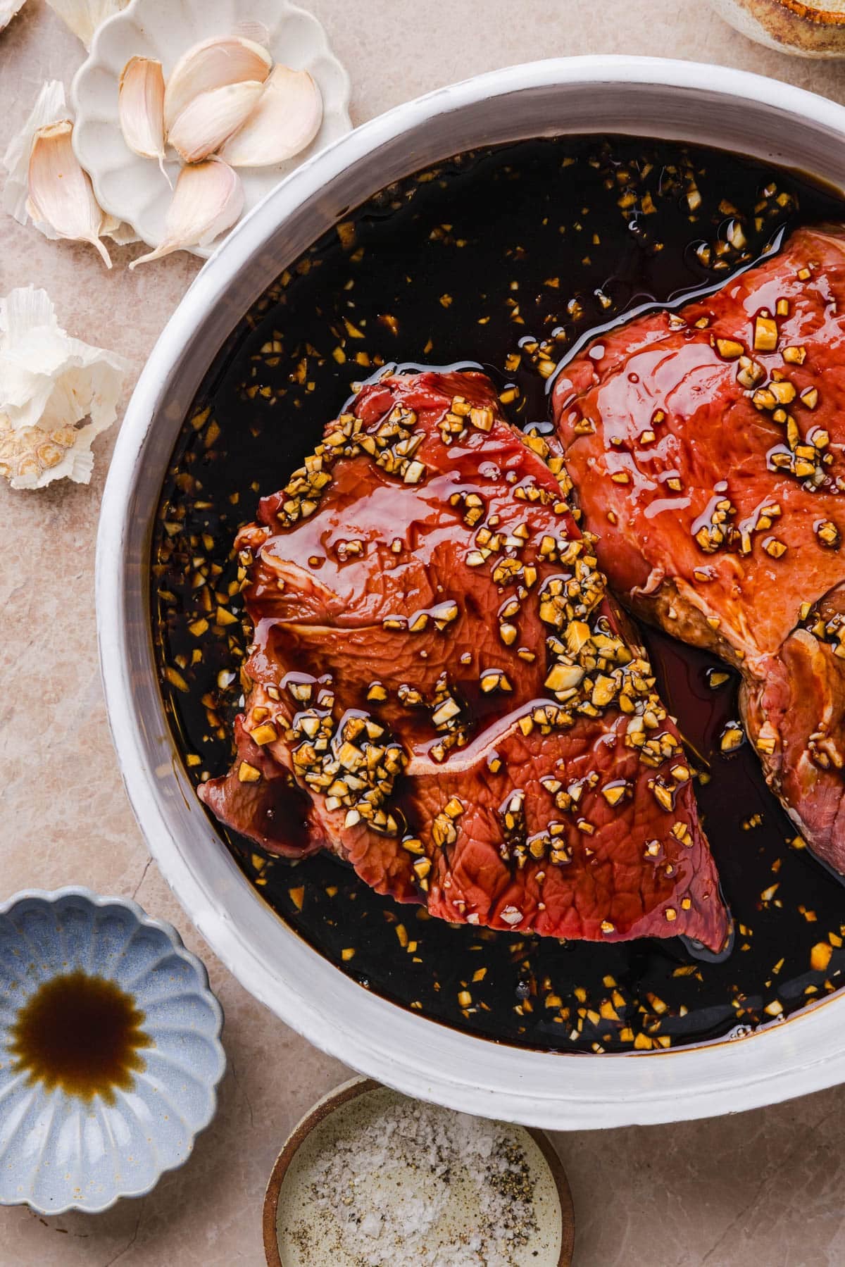The steak marinating in the steak marinade in a shallow bowl.