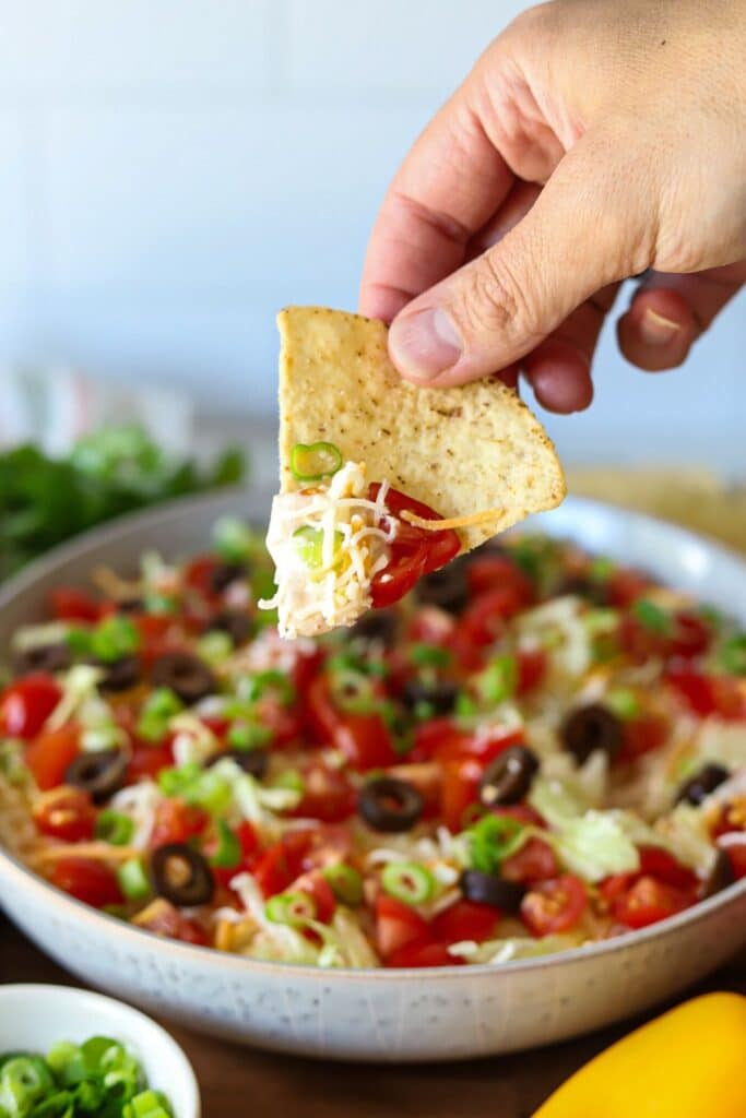 A chip dipping into cottage cheese taco dip.