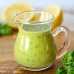 Lemon basil vinaigrette dressing in a glass dressing container.