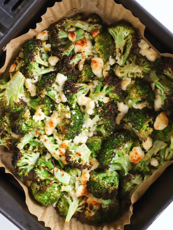 Air fryer broccoli and feta cheese in an air fryer basket.