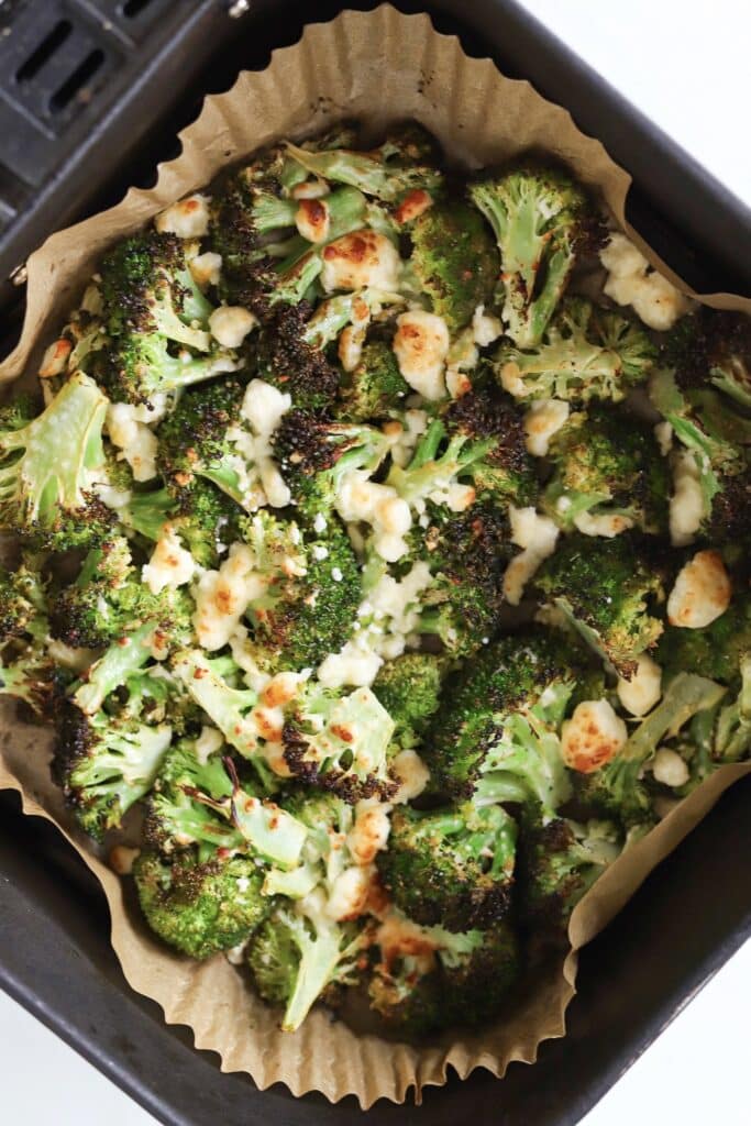 Air fryer broccoli and feta cheese in an air fryer basket.
