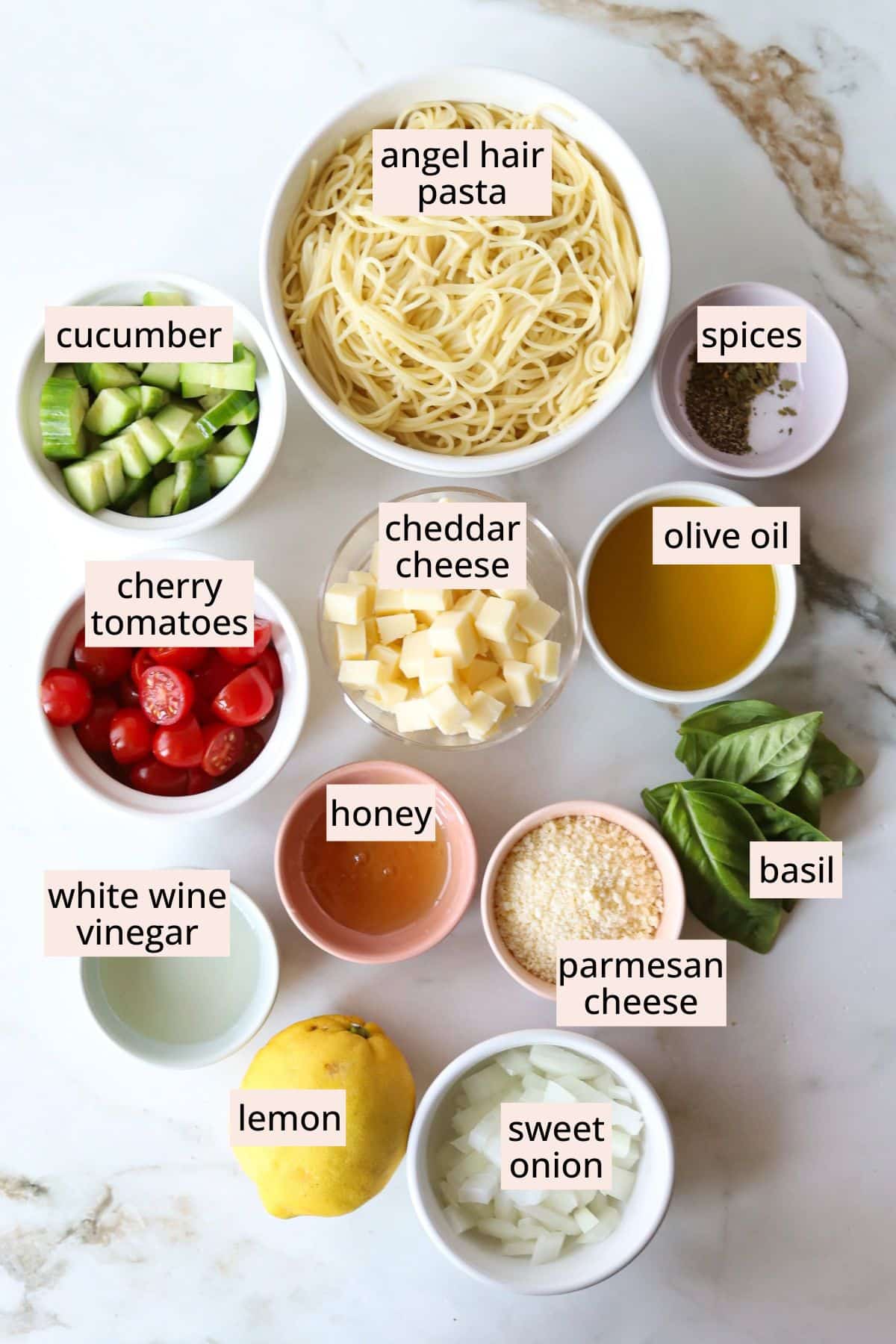 Ingredients for angel hair pasta salad on a countertop with labels.