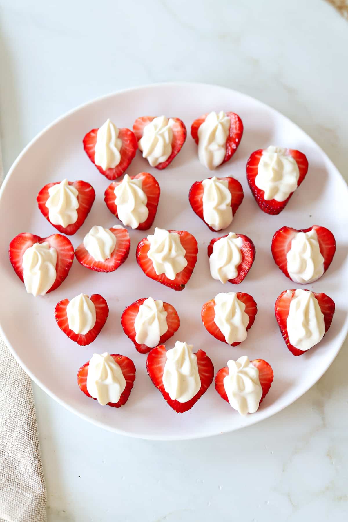Strawberries filled with a Greek yogurt cream cheese mixture on a platter.