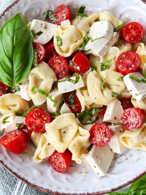 Tortellini caprese salad in a bowl garnished with extra basil.