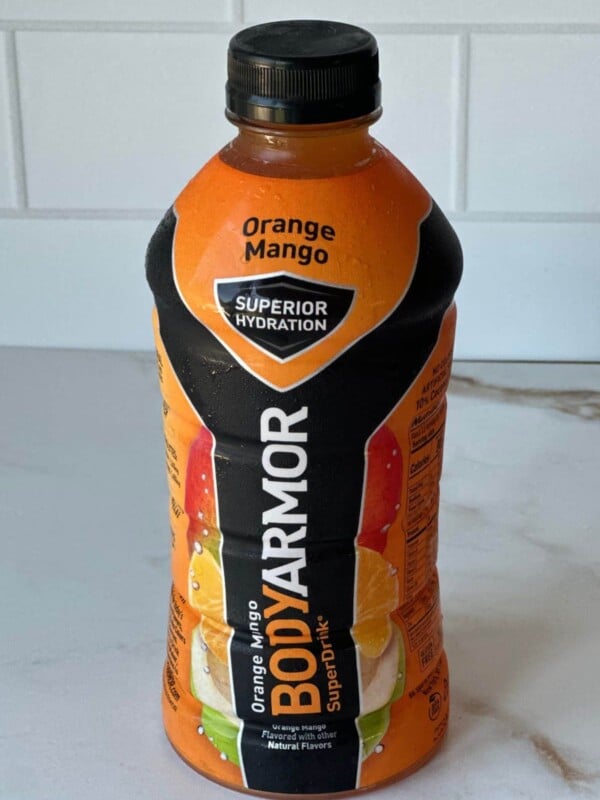 A bottle of orange mango body armor on a countertop.