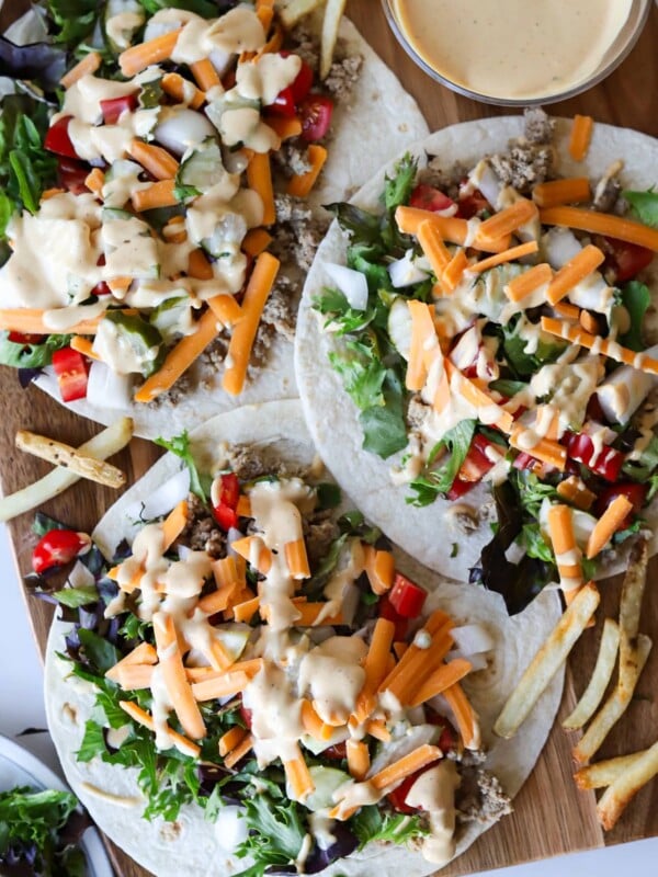 Big mac wraps on a wooden board with sauce.