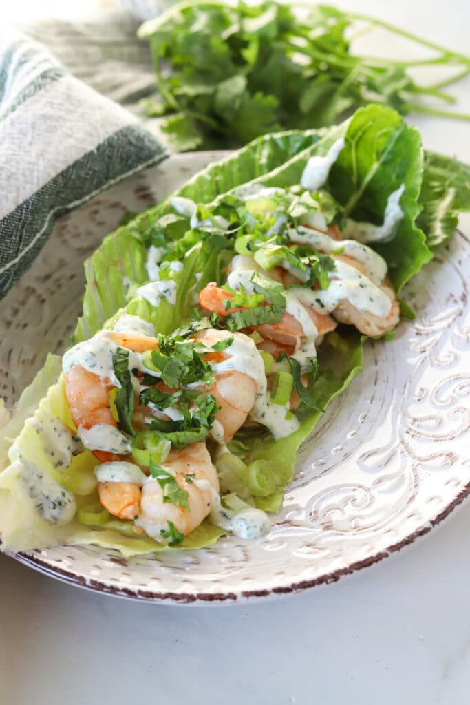 Cilantro lime shrimp wraps topped with garlic cilantro sauce on a plate.