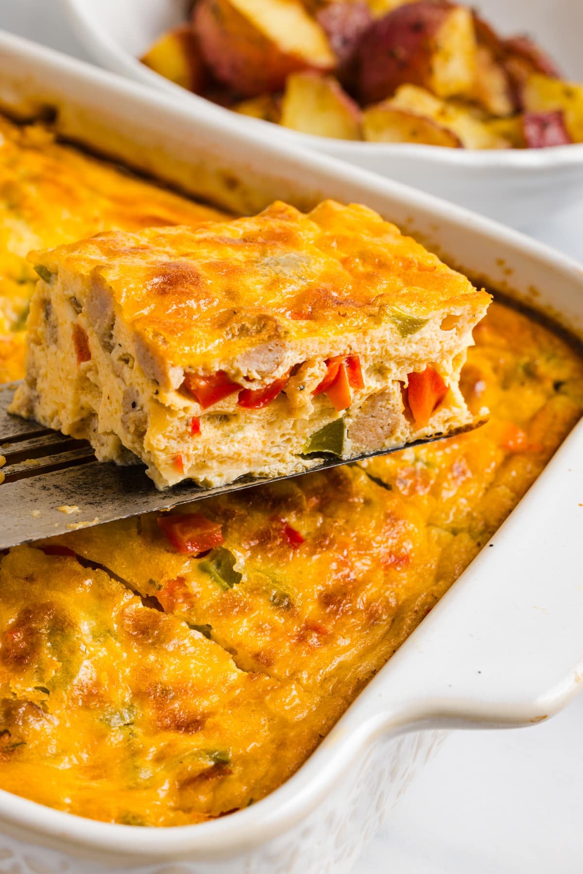 A spatula lifts a slice of cottage cheese egg bake from the casserole dish for serving.