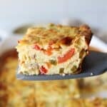A slice of cottage cheese egg bake being held up in front of the camera by a spatula.