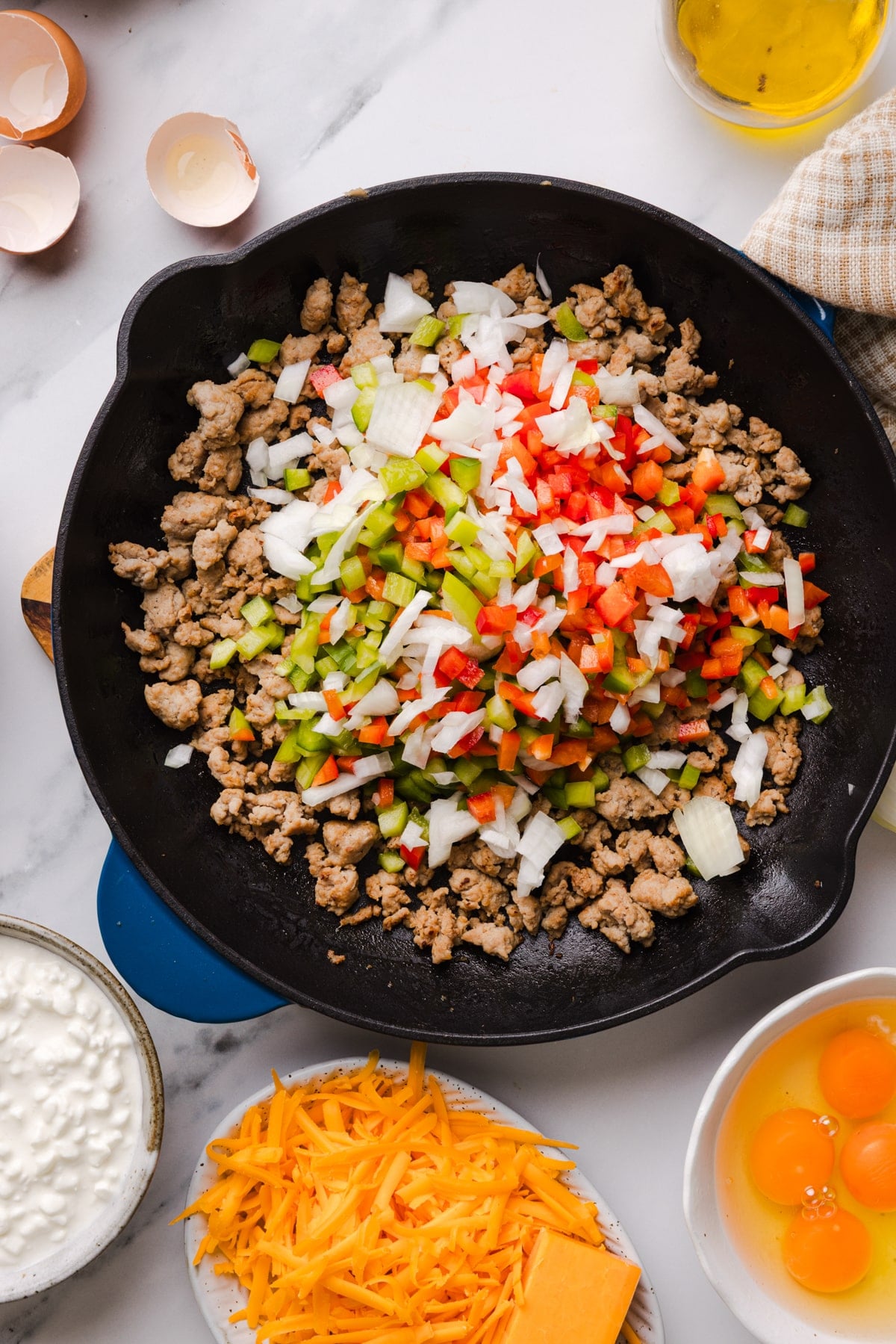 The cooked sausage with the peppers and onions in a large cast iron skillet.