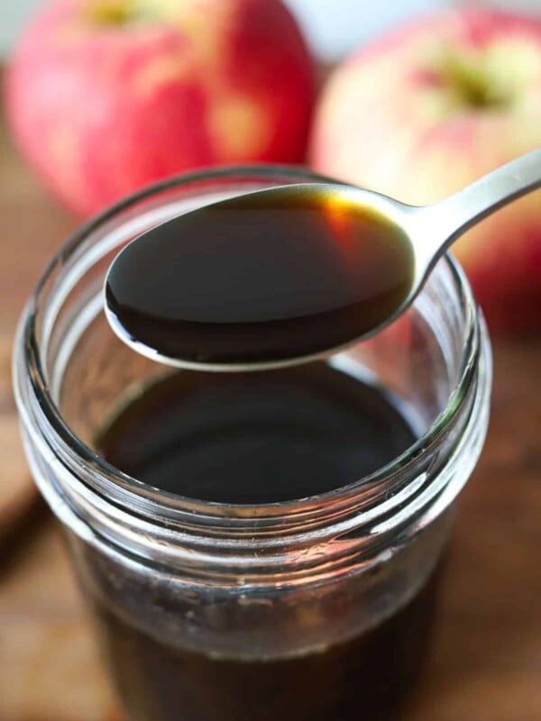 A spoonful of apple brown sugar syrup above a jar.