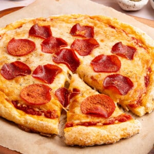 Cottage cheese pizza with pepperoni on top sitting on a piece of brown parchment paper
