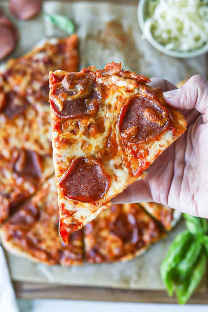 A close up shot of cottage cheese pizza crust being held up.