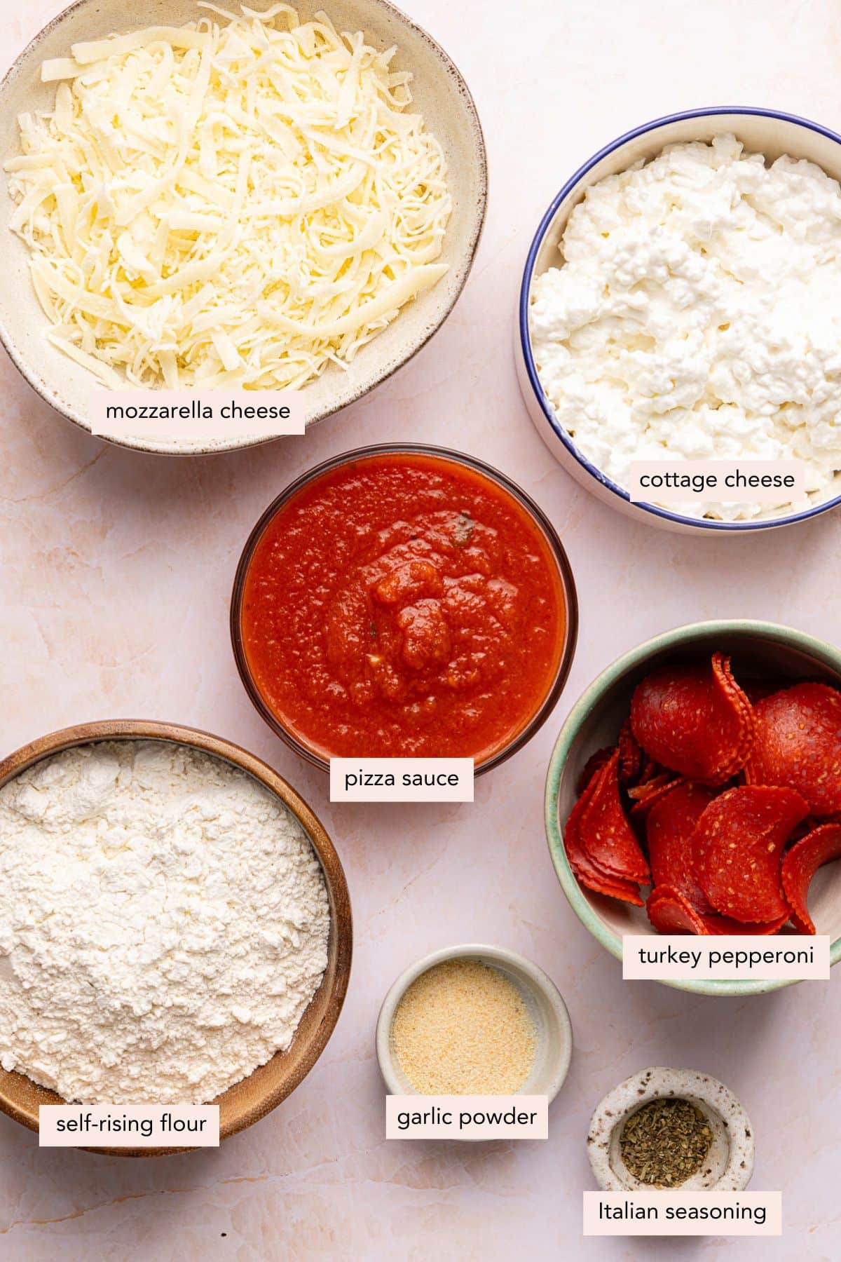 All of the ingredients for cottage cheese pizza in bowls on a countertop.