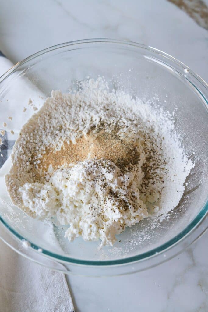 Cottage cheese, self-rising flour and spices in a bowl.