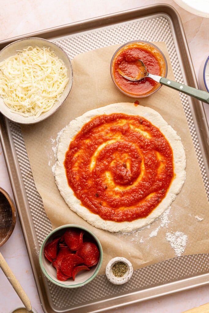 The sauce spread on top of the round crust before baking.