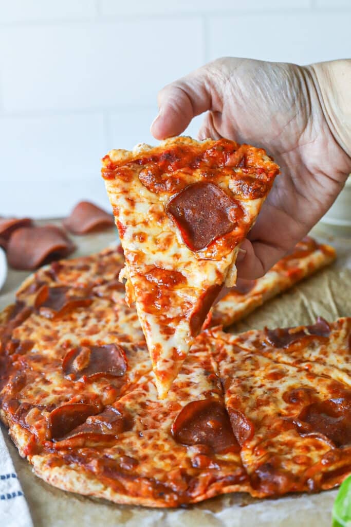A slice of cottage cheese pizza crust being held up