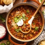A ladle rests in a pan of hearty ground chicken chili.