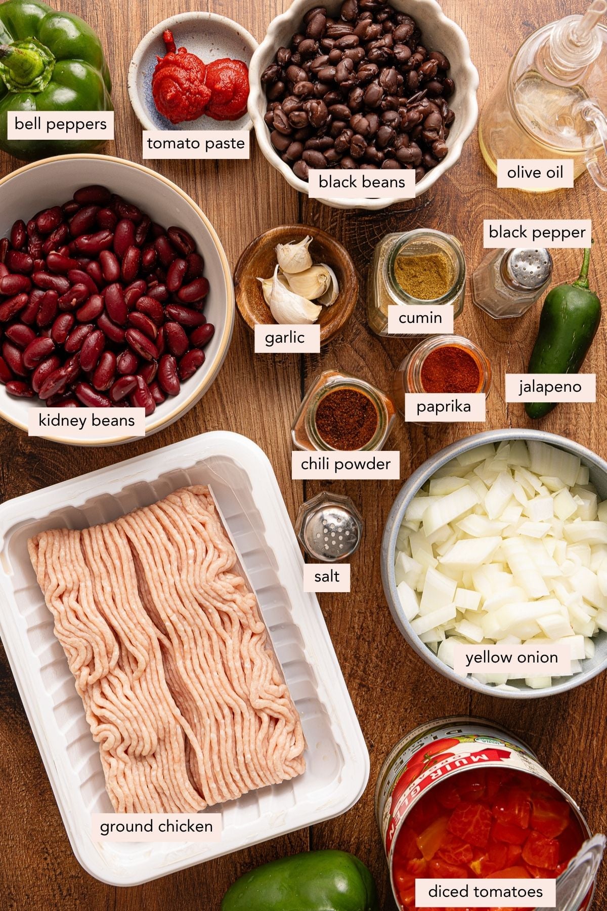All of the ingredients for ground chicken chili in bowls on a countertop.