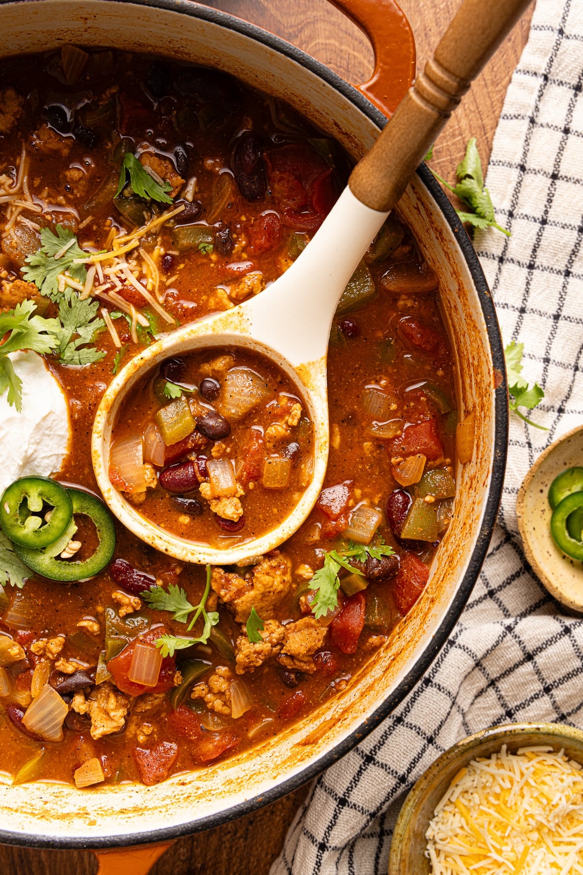 A ladle rests in a dutch oven filled with ground chicken chili.