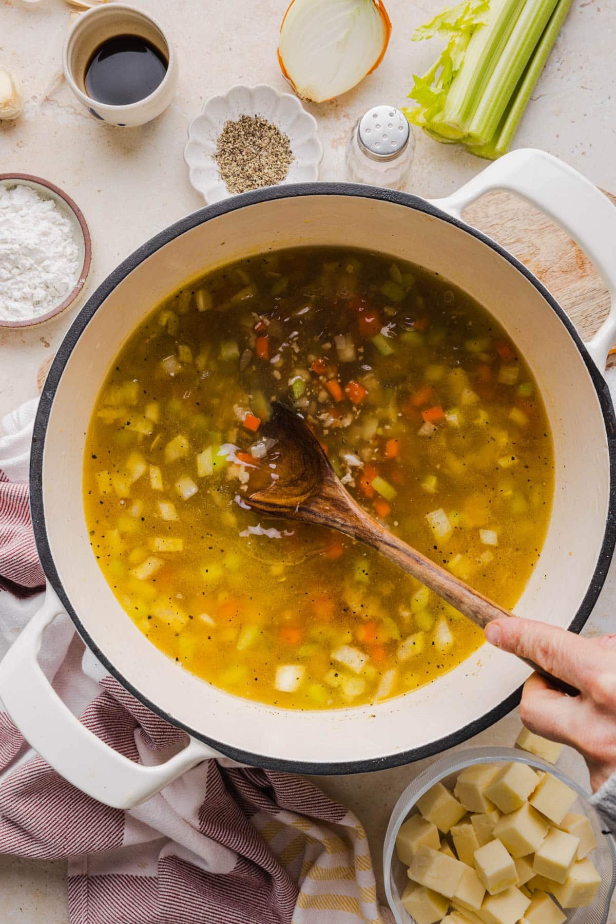The broth in the pot with the cooked vegetables and turkey. A spoon is stirring the mixture.