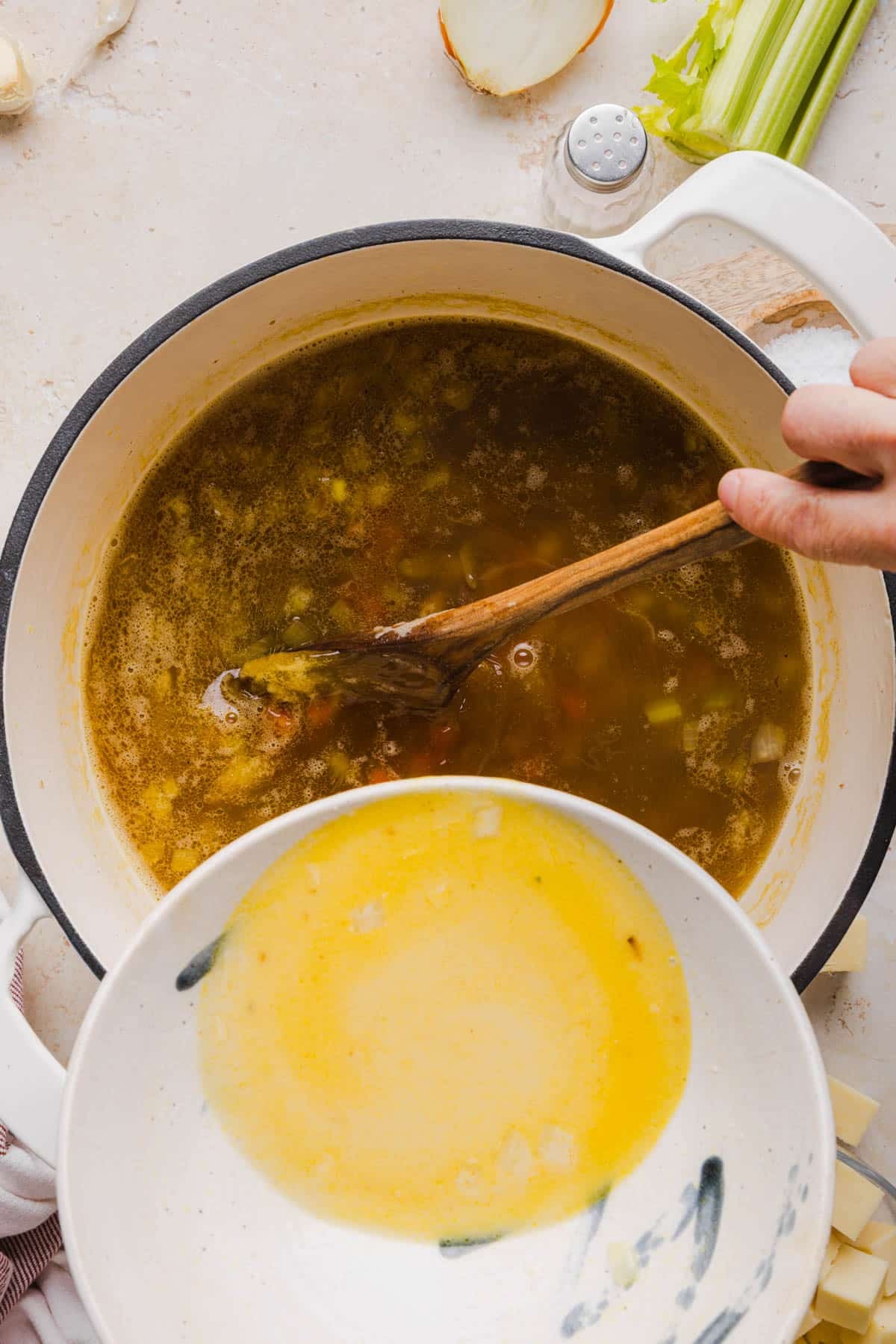Pouring the whisked broth flour mixture into the remaining ingredients in the pot.