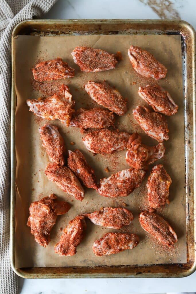 Buffalo chicken wings made with a dry rub on a baking sheet.