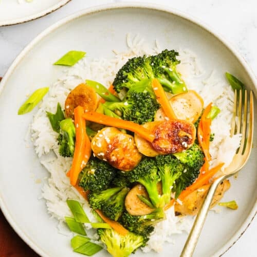 Chicken sausage broccoli stir-fry plated and garnished with green onions and sesame seeds.