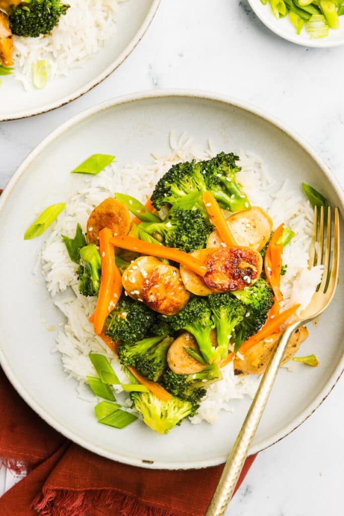 Chicken sausage broccoli stir-fry plated and garnished with green onions and sesame seeds.