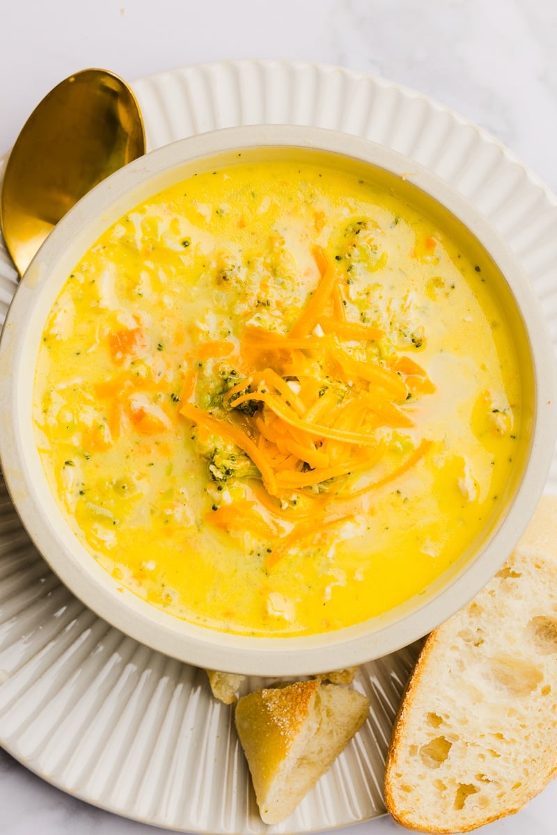 Chicken broccoli cheddar soup in a bowl topped with cheddar cheese.